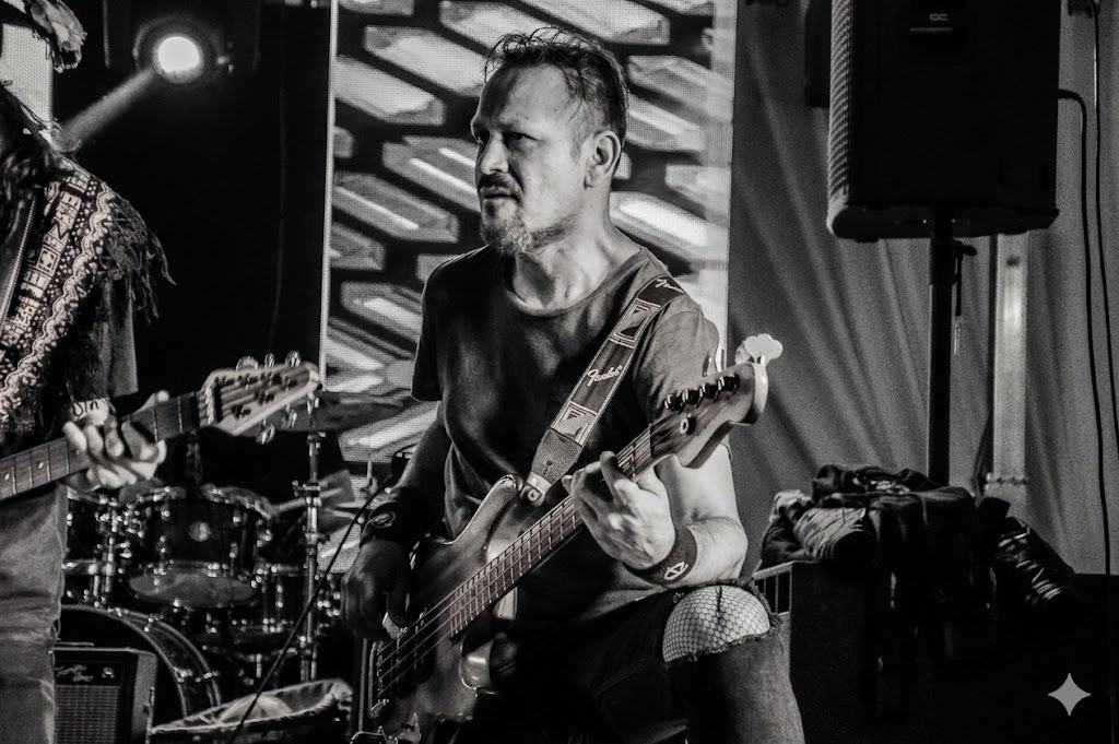 Retrato en blanco y negro de Miguel Tuesta tocando el bajo en escenario